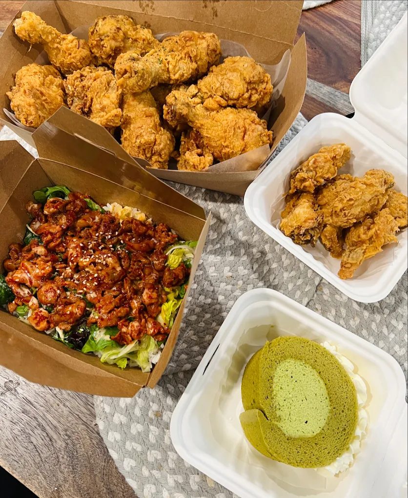 Takeout spread of fried chicken, spicy pork, and matcha roll cake